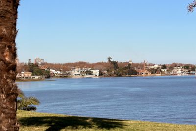 Scenic view of sea by buildings against clear blue sky