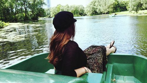 Rear view of woman sitting by lake