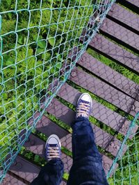 Low section of person standing on metal fence