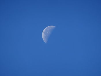 Low angle view of moon in blue sky