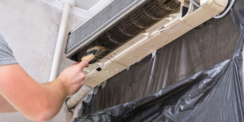 Cropped hand of repairman repairing air conditioner