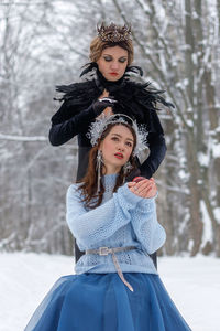 Portrait of young woman standing on snow covered field