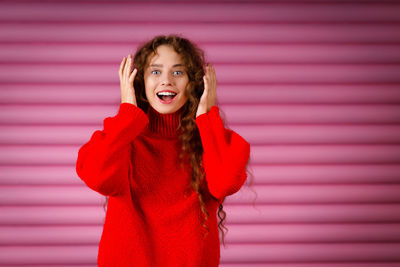 Portrait of young woman standing against wall