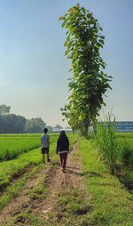 Rear view of woman walking on field against sky