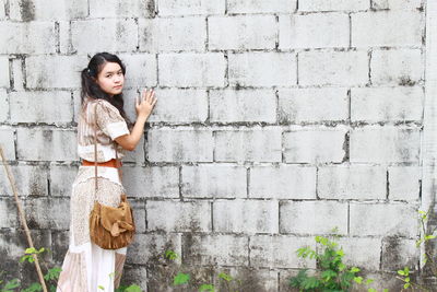 Portrait of woman standing against wall