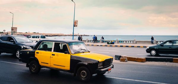 Traffic on road by sea against sky