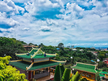 High angle view of trees and buildings against cloudy sky