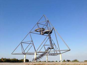 Metallic structure on land against clear blue sky