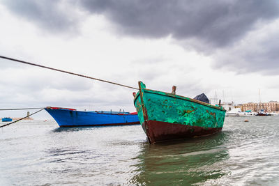 Fishing boat moored at beach against sky