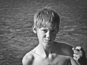 Thoughtful shirtless boy looking away against sea