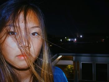 Close-up portrait of young woman against sky at night