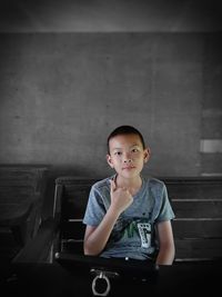 Portrait of boy sitting on bench by mobile phone over table