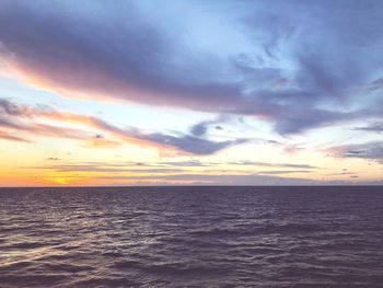 Scenic view of sea against dramatic sky during sunset