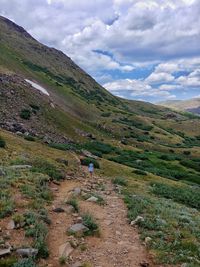 Rear view of person walking on landscape against sky