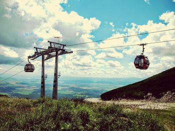 Overhead cable cars on field against sky