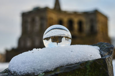 Close-up of crystal ball on snow against building