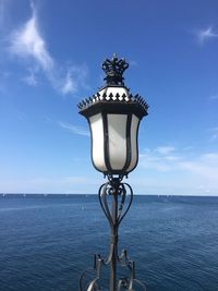 Lamp post by sea against blue sky