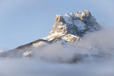 Mountain peak catching first sun rays during sunrise, three sisters mountain, canmore, canada
