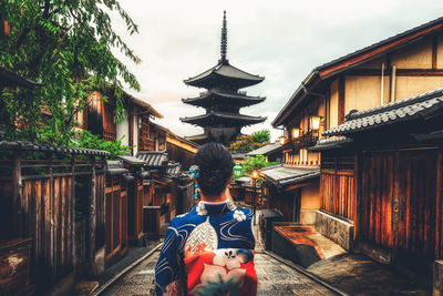 Rear view of man walking in temple outside building