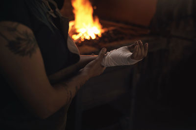 Midsection of woman holding burning at night