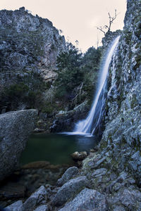 Scenic view of waterfall against sky