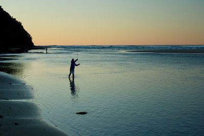 Silhouette man on beach against sky during sunset