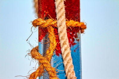 Close-up of rope tied up against blue sky