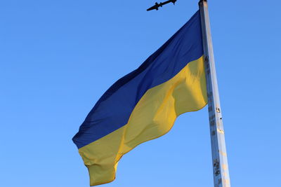 Low angle view of flag against blue sky