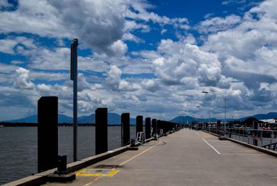 View of pier on river against cloudy sky