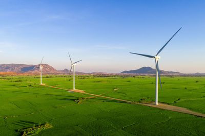 Windmills on field against sky