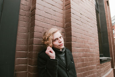 Portrait of young man wearing warm clothing against wall