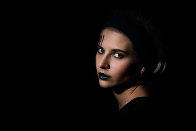 Close-up portrait of a young woman over black background