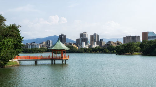 Buildings by river against sky in city