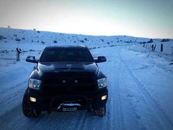 Cars on snow covered landscape against clear sky