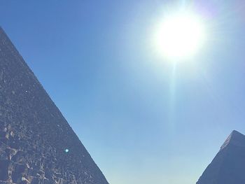 Low angle view of sun shining through blue sky