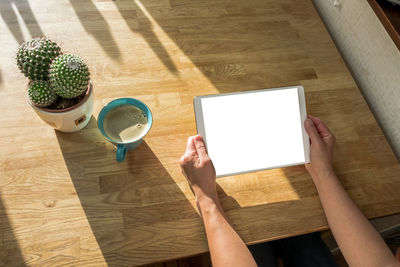 High angle view of hand holding coffee cup on table