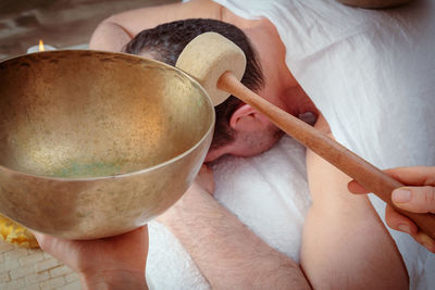 A woman performs tibetan singing bowl therapy with a man lying under a white sheet. 