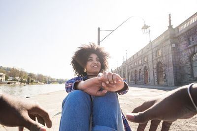 Smiling young woman with curly hair sitting outdoors in city