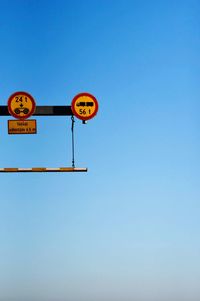 Low angle view of road sign against clear blue sky