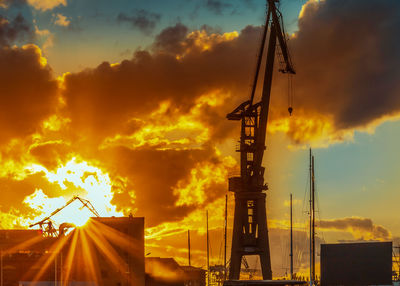 Low angle view of silhouette cranes against sky during sunset