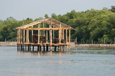 Wooden house by lake against sky