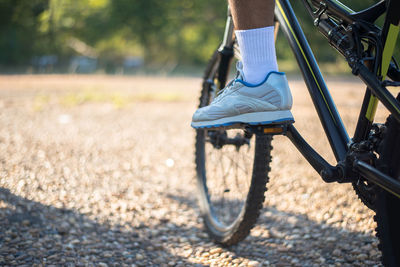 Low section of man riding bicycle on road