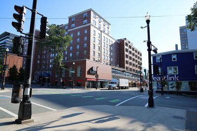 Road by buildings against clear sky