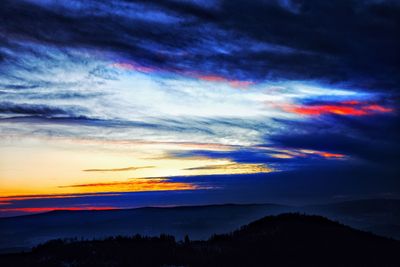 Scenic view of dramatic sky over silhouette landscape