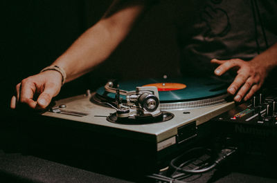 Midsection of man adjusting turntable in darkroom