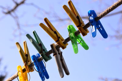 Low angle view of clothespins on clothesline against sky