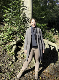 Portrait of smiling young woman standing in forest