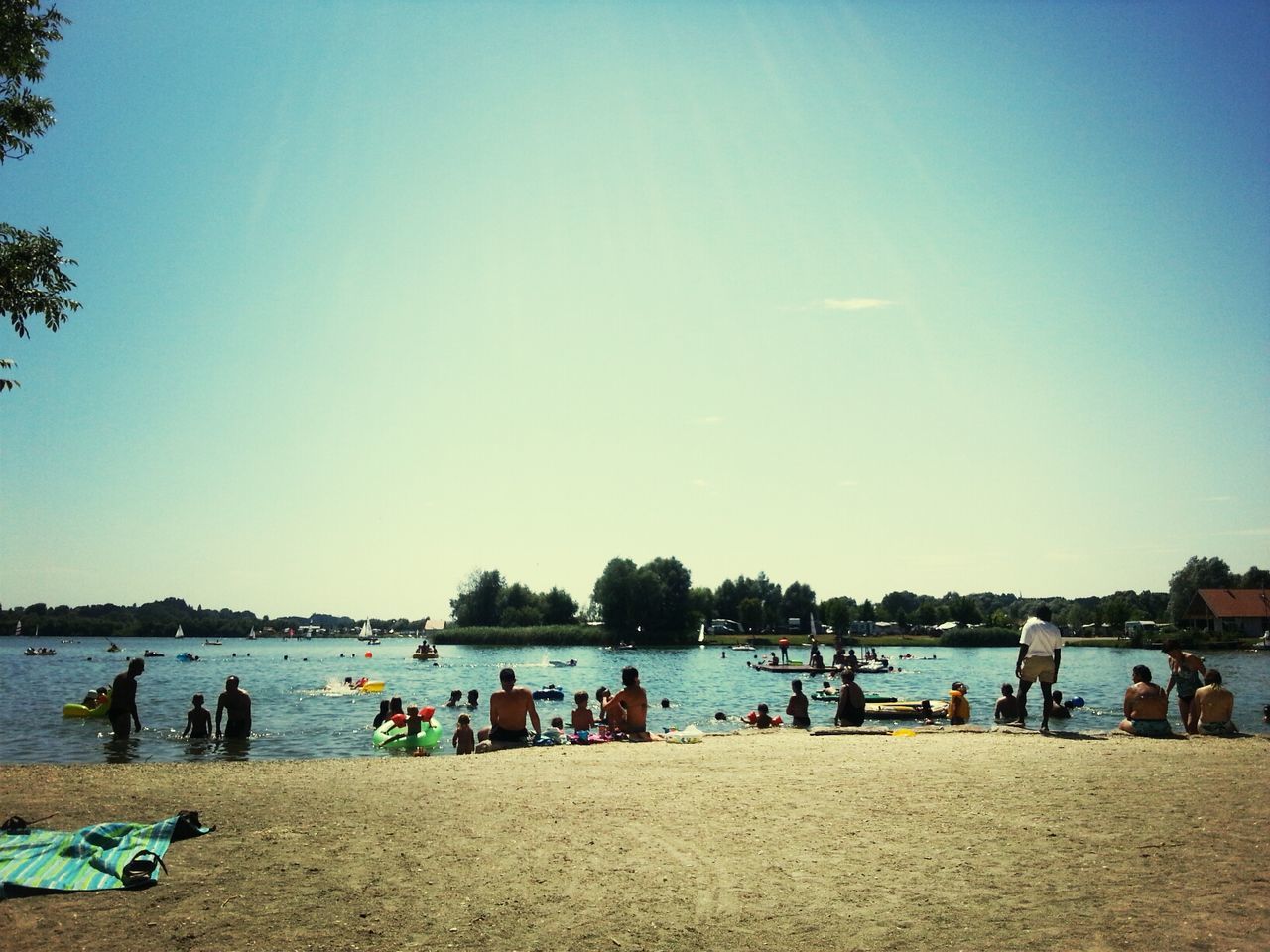 large group of people, water, clear sky, beach, leisure activity, copy space, lifestyles, vacations, blue, person, sea, men, enjoyment, mixed age range, relaxation, shore, tourist, enjoying, weekend activities