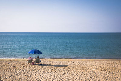 Rear view of person on beach against clear sky