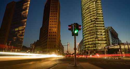 Light trails on city street against clear sky at night